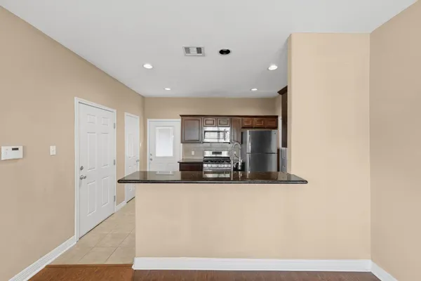 a large white kitchen with kitchen island stainless steel appliances a sink and a refrigerator