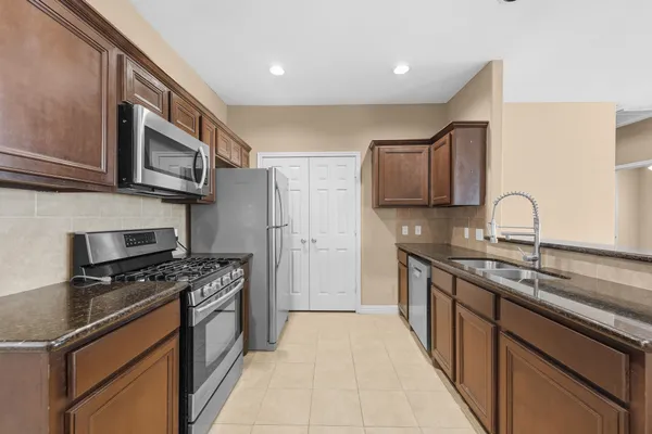 a kitchen with stainless steel appliances granite countertop a stove a sink and a microwave