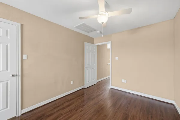 an empty room with wooden floor fan and window
