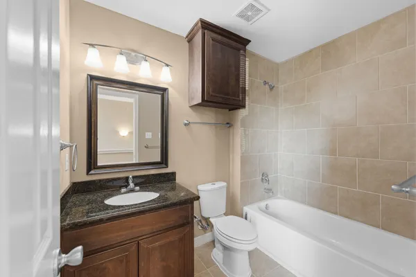 a bathroom with a granite countertop sink toilet and mirror