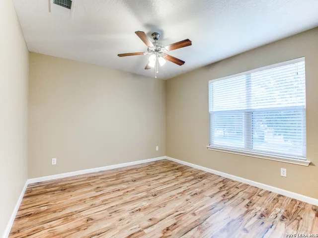a view of an empty room with window and wooden floor