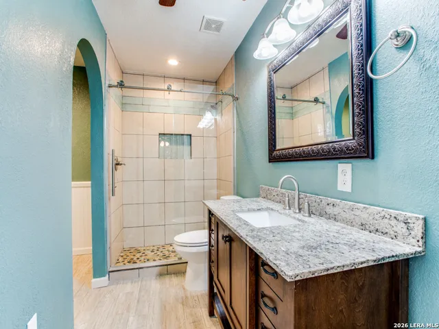 a bathroom with a granite countertop sink a mirror and shower