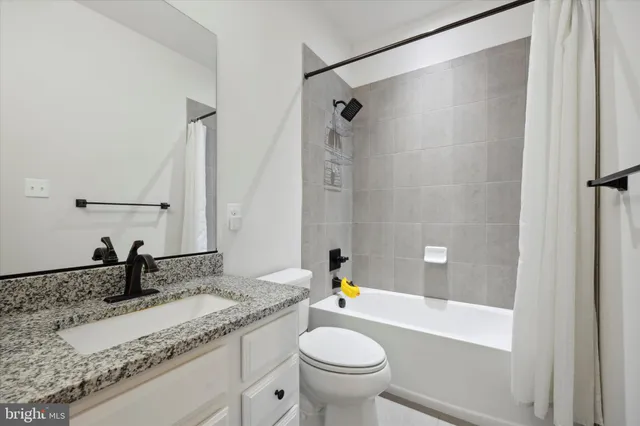 a bathroom with a granite countertop sink a toilet and shower