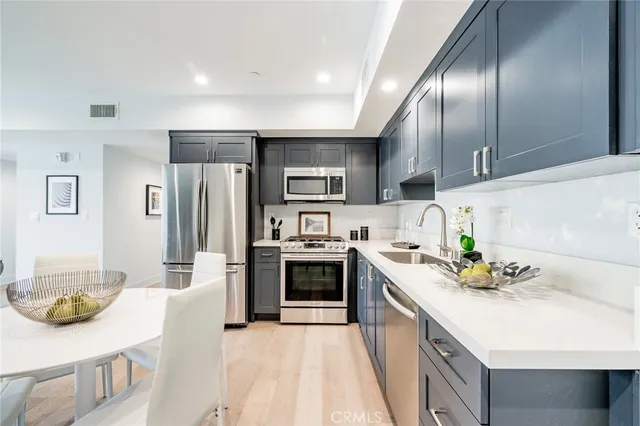 a kitchen with stainless steel appliances kitchen island granite countertop a refrigerator and a stove top oven