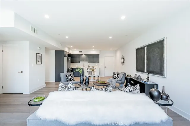 a living room with furniture a rug kitchen view and a chair