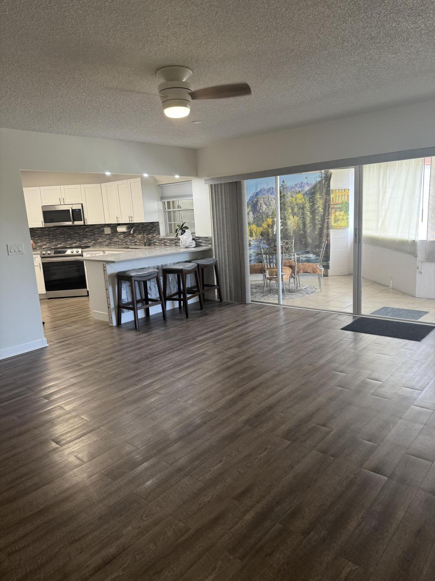 4 Greenway Village North, Unit 203 Royal Palm Beach, FL 33411 - Photo 4 of 19 a view of a kitchen with dining area wooden floor and windows