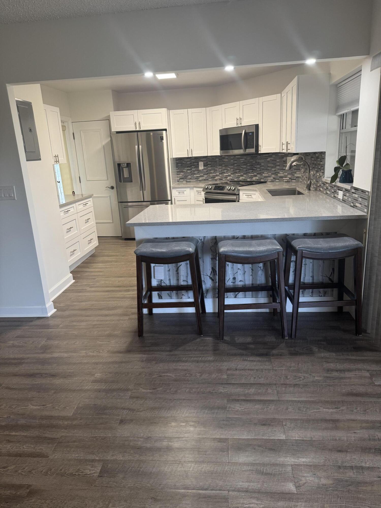 4 Greenway Village North, Unit 203 Royal Palm Beach, FL 33411 - Photo 5 of 19 a kitchen with stainless steel appliances granite countertop a table chairs sink and cabinets