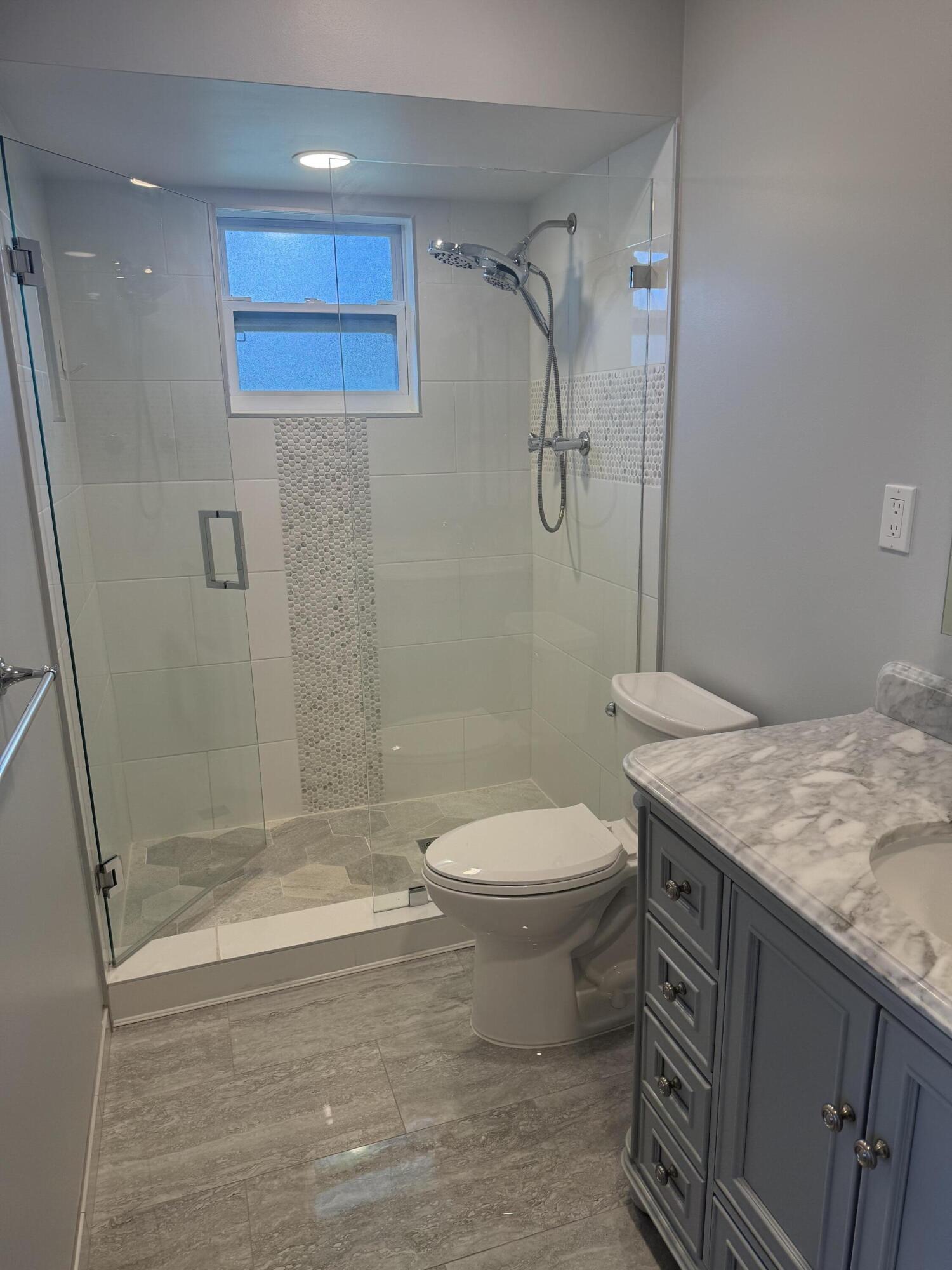 4 Greenway Village North, Unit 203 Royal Palm Beach, FL 33411 - Photo 9 of 19 a bathroom with a granite countertop sink a toilet and shower