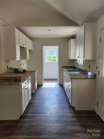 a kitchen with granite countertop white cabinets and sink