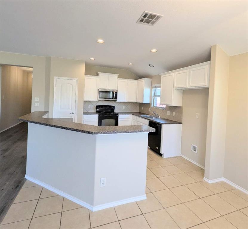 2110 Spruce Street Anna, TX 75409 - Photo 5 of 13 a kitchen with kitchen island granite countertop white cabinets and stainless steel appliances
