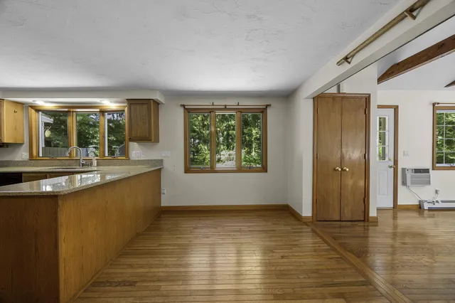 a view of an empty room with window and wooden floor