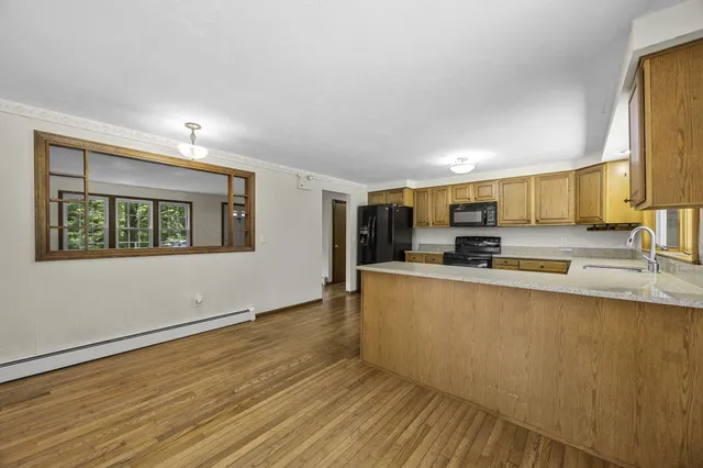 a view of a kitchen with kitchen island wooden floor and stainless steel appliances