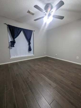 an empty room with wooden floor and fan