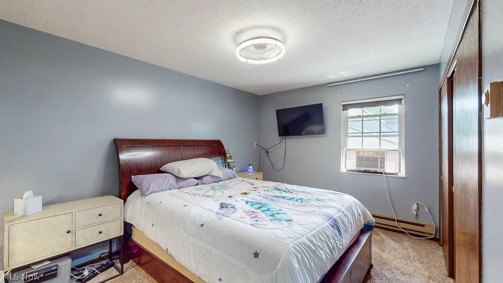 38667 Chestnut Ridge Road Elyria, OH 44035 - Photo 14 of 35 Carpeted bedroom featuring a window with an installed air conditioning unit, a ceiling-mounted light fixture, and two built-in closet doors with wood-finish panels