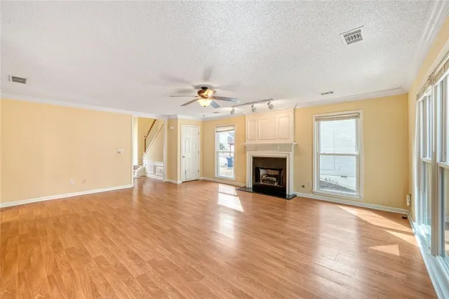 an empty room with wooden floor fireplace and windows