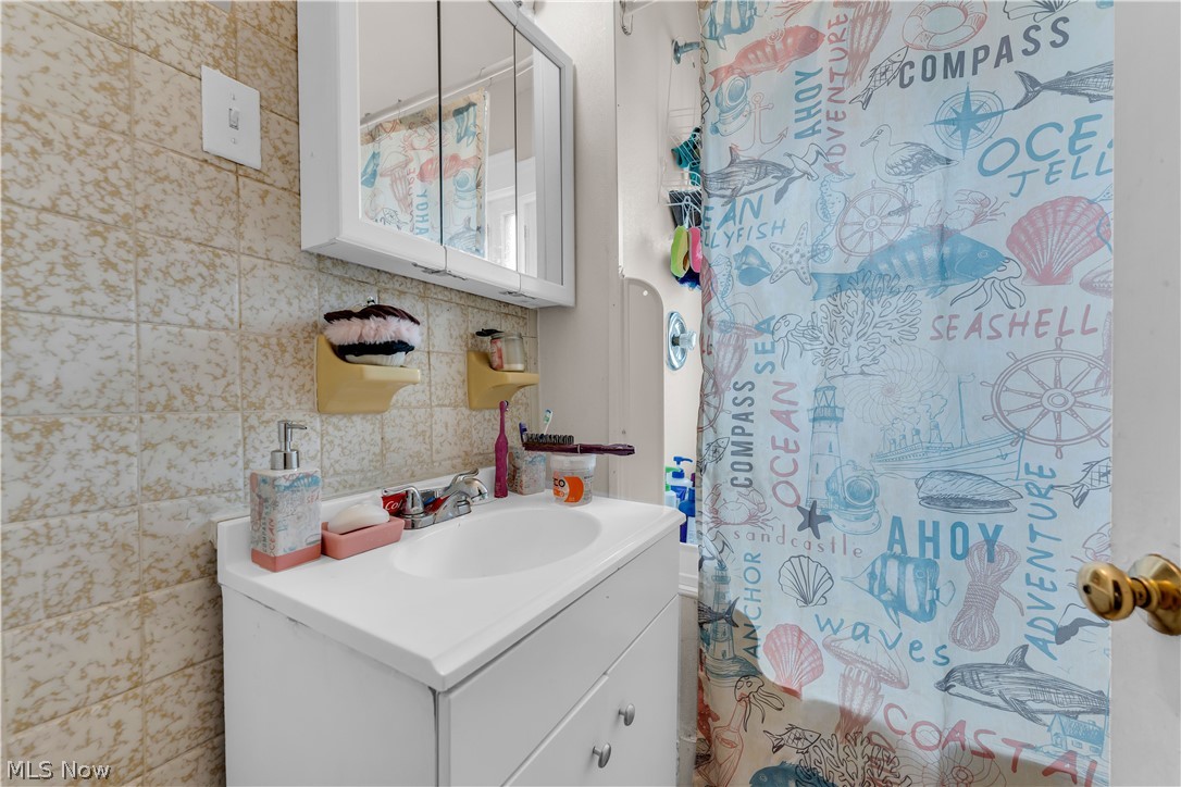 975 Yellowstone Road Cleveland Heights, OH 44121 - Photo 15 of 19 Bathroom featuring vanity, decorative backsplash, and tile walls
