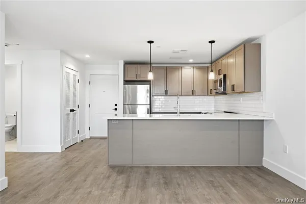 a large kitchen with granite countertop a white stove top oven a sink and white cabinets
