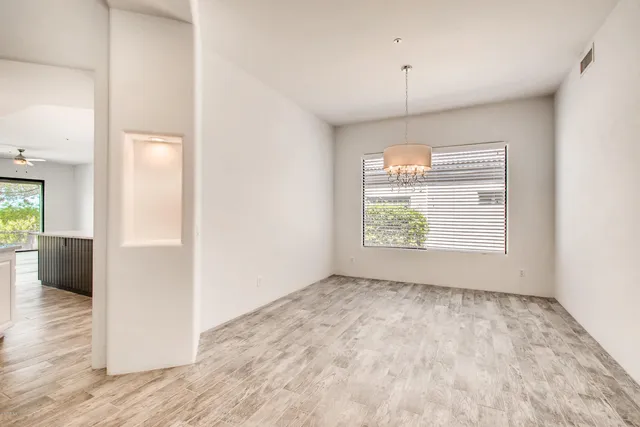 an empty room with wooden floor cabinet and windows