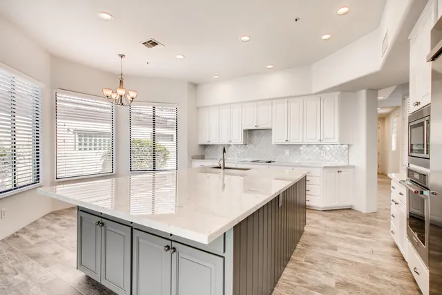 a large kitchen with kitchen island a large counter top space a sink stainless steel appliances and cabinets
