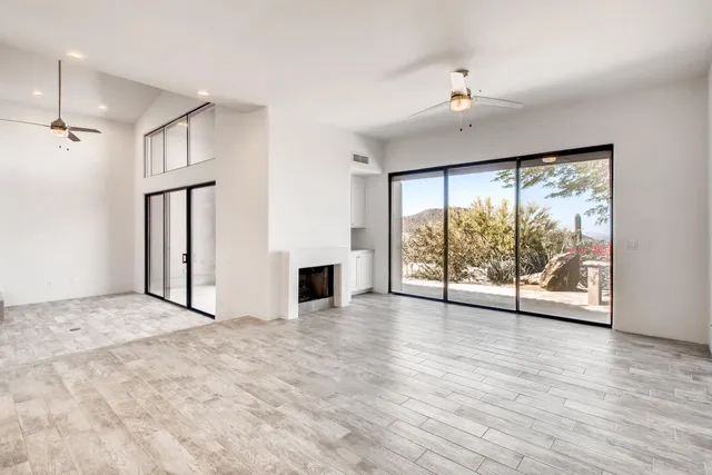 an empty room with windows and ceiling fan