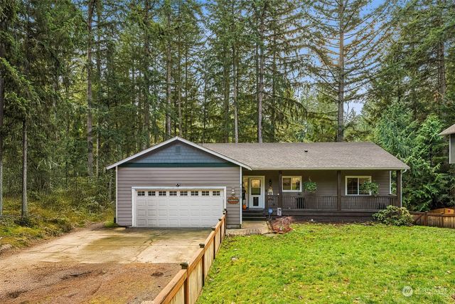 a view of a house with a yard plants and large tree