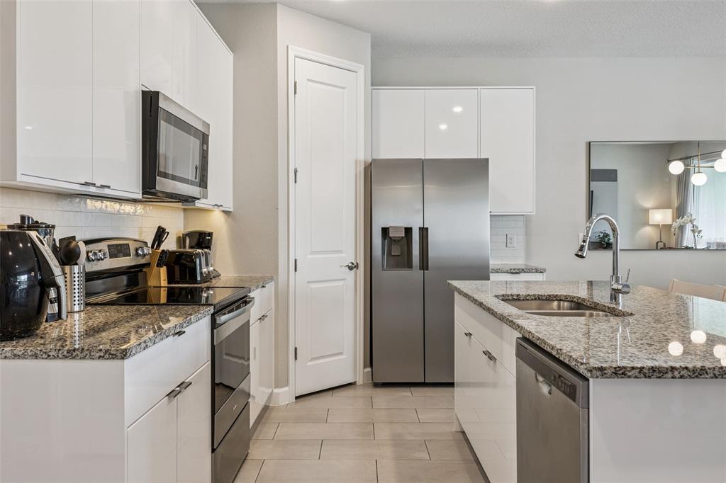8008 Formosa Valley Place Kissimmee, FL 34747 - Photo 11 of 55 a kitchen with stainless steel appliances granite countertop a sink stove and refrigerator