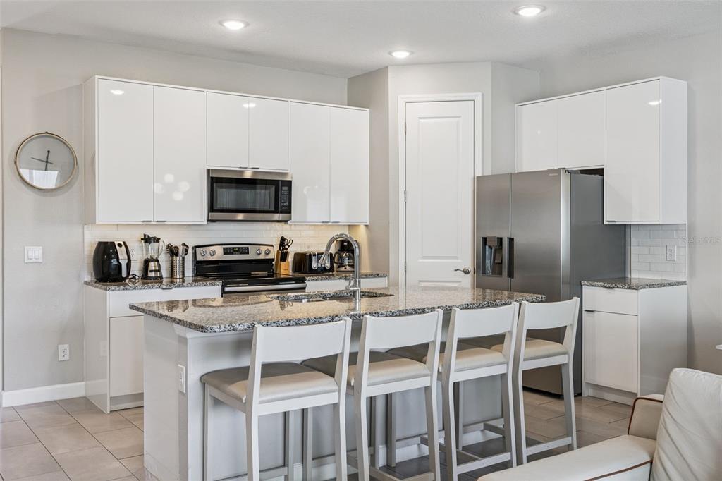 8008 Formosa Valley Place Kissimmee, FL 34747 - Photo 8 of 55 a kitchen with stainless steel appliances granite countertop a stove a sink a microwave a refrigerator and chairs