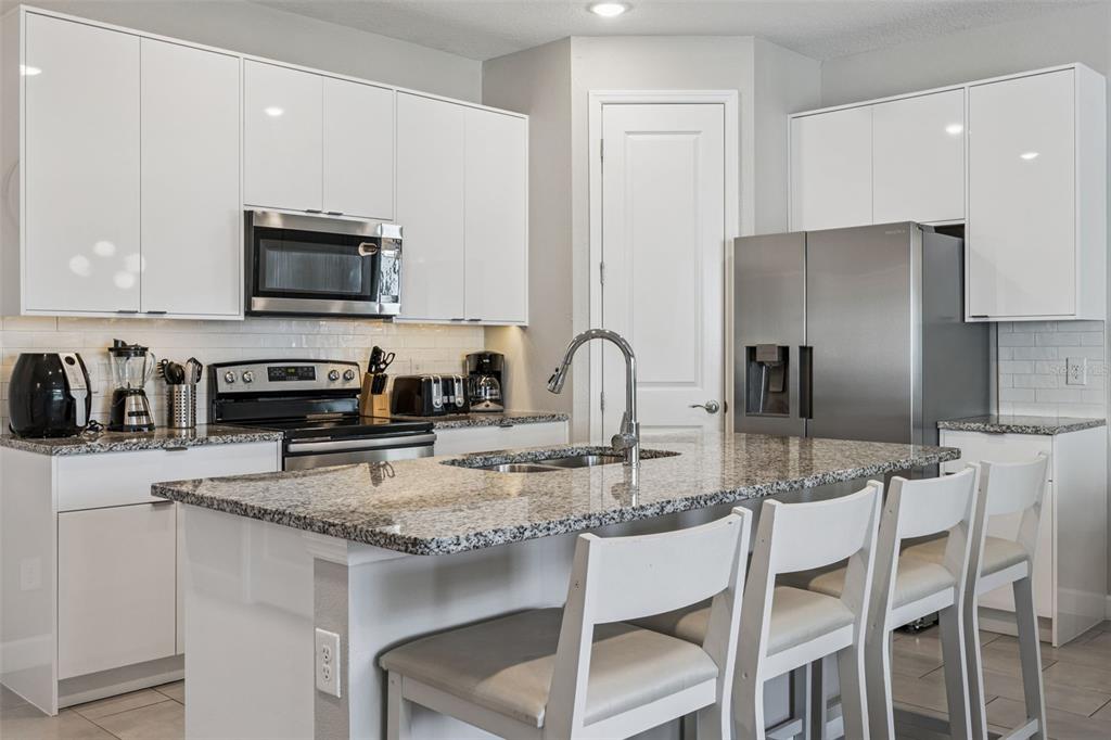 8008 Formosa Valley Place Kissimmee, FL 34747 - Photo 9 of 55 a kitchen with stainless steel appliances granite countertop a stove a sink a microwave a refrigerator and white cabinets