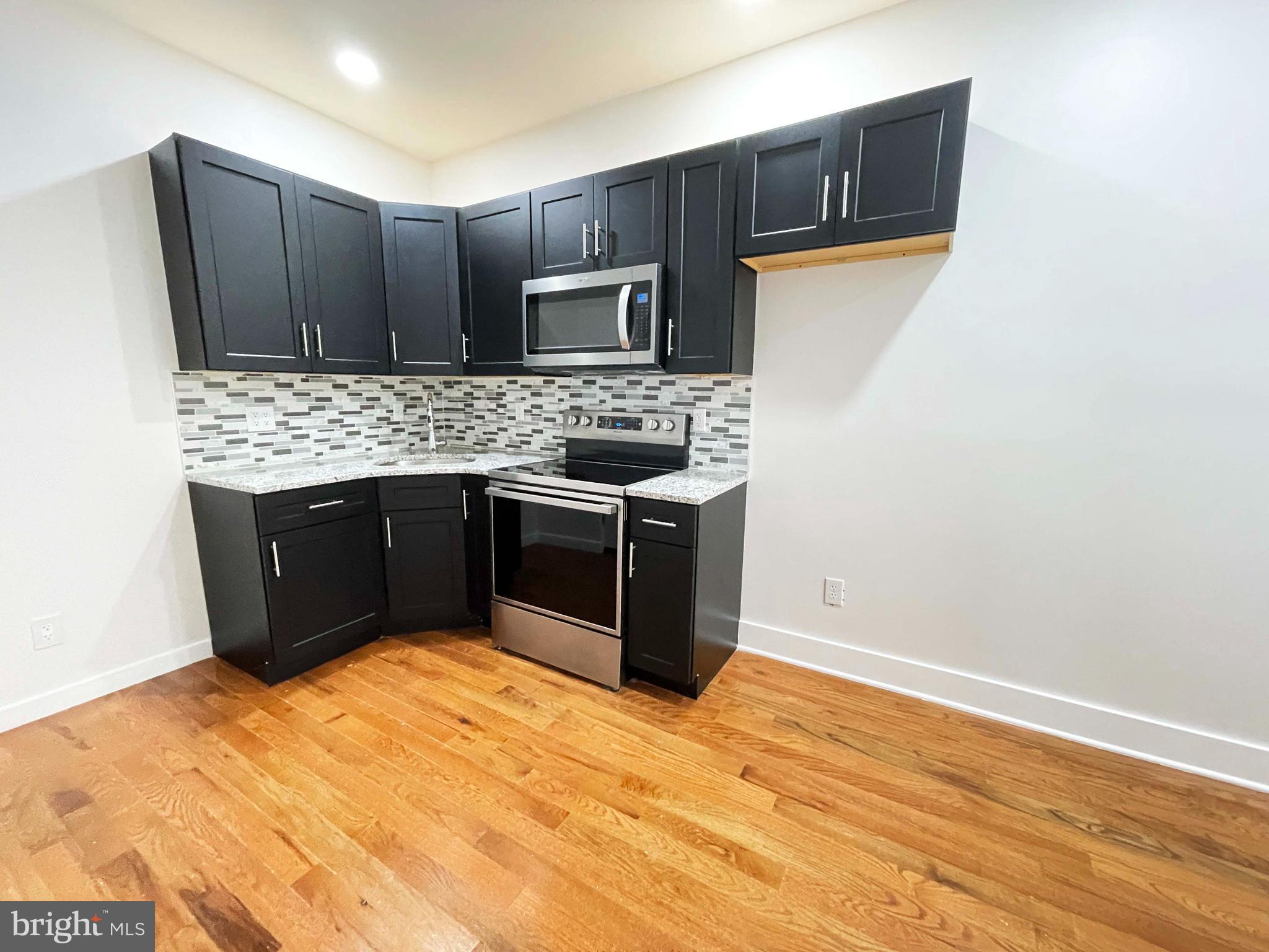 309 South 60th Street, Unit 1 Philadelphia, PA 19143 - Photo 8 of 17 a kitchen with stainless steel appliances granite countertop a stove a sink and a microwave