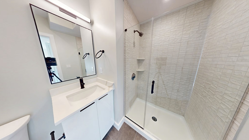 211 Green Street, Unit 401 Boston, MA 02130 - Photo 6 of 11 a bathroom with a sink a mirror and shower
