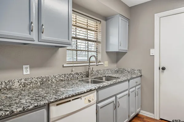 a kitchen with granite countertop a sink and a white wooden cabinets