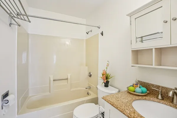 a bathroom with a granite countertop tub sink and mirror