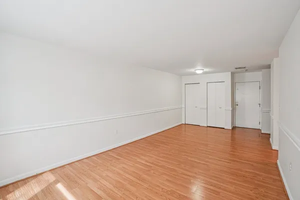 an empty room with wooden floor and windows