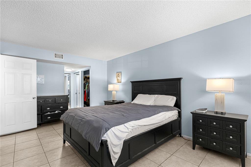 588 Fairways Lane, Unit E201 Ocala, FL 34472 - Photo 14 of 33 a bedroom with a bed and a lamp on dresser