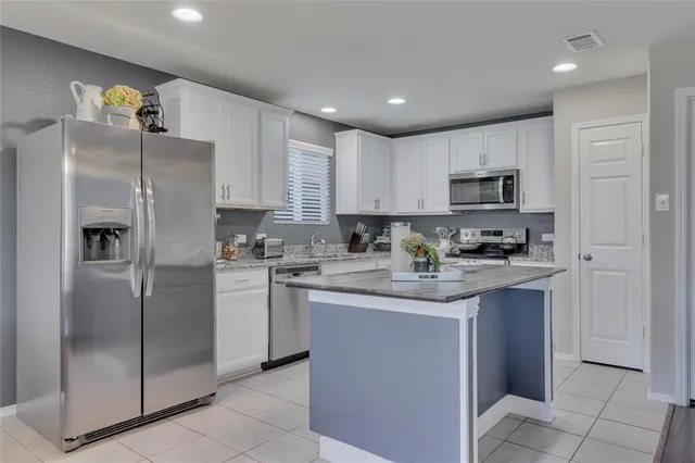 a kitchen with kitchen island granite countertop a refrigerator stove top oven and sink