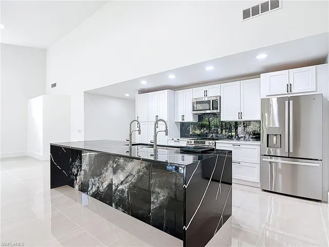 a kitchen with stainless steel appliances granite countertop a refrigerator a stove and a sink