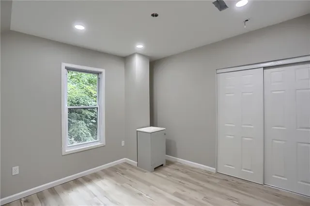 a view of an empty room with a window and wooden floor