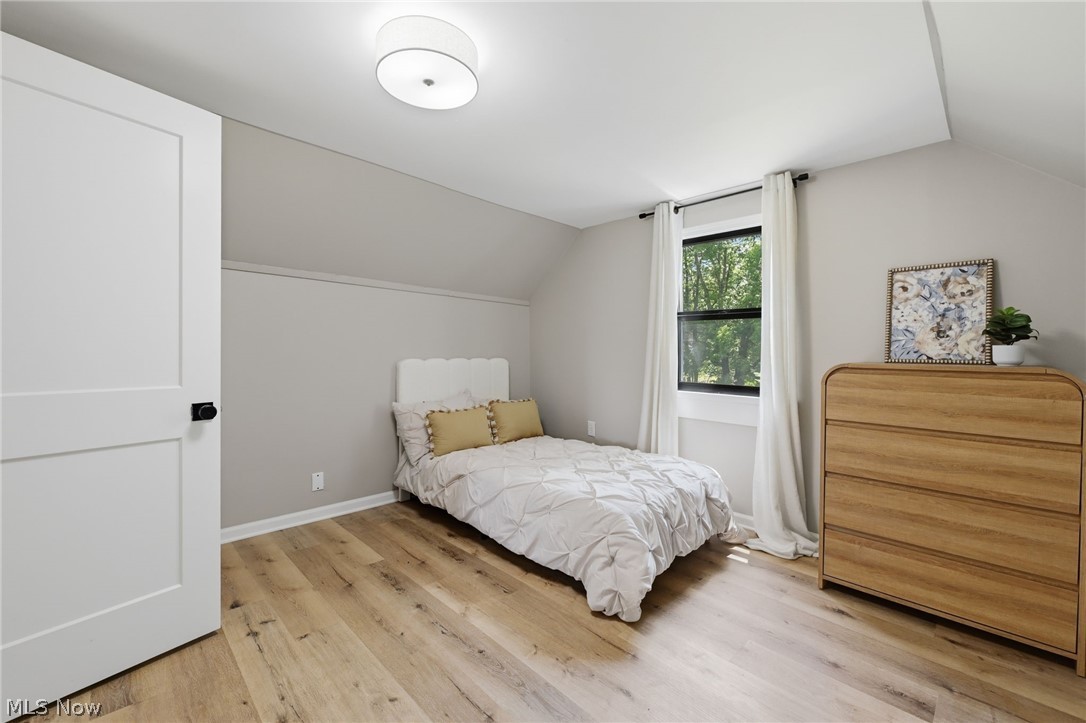951 Bey Road Akron, OH 44312 - Photo 21 of 34 Second floor bedroom featuring wood-finish flooring, a contemporary flush-mount ceiling light, a white flat-panel door with black hardware, and a window with exterior views