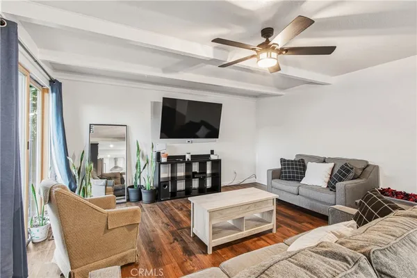 a living room with furniture a ceiling fan and a flat screen tv