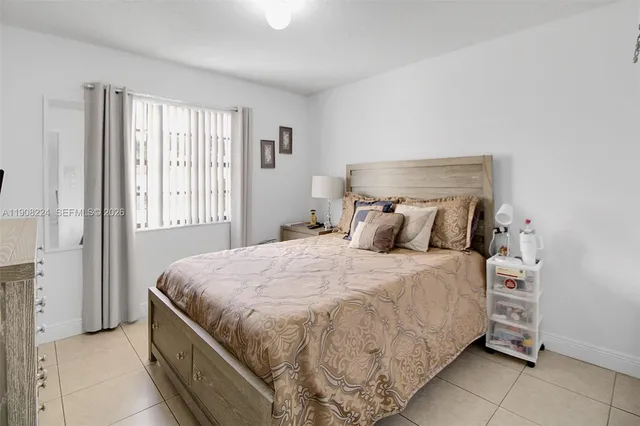 a bed sitting in a bedroom next to a window and a chair