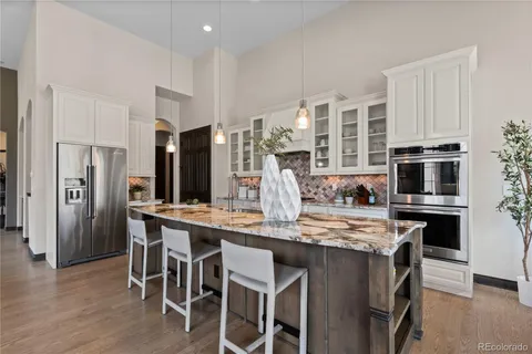 a kitchen with stainless steel appliances granite countertop a table chairs stove refrigerator and cabinets