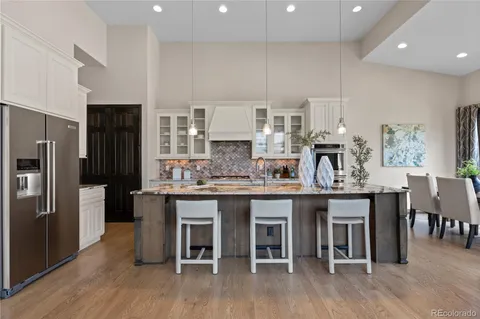 a kitchen with stainless steel appliances granite countertop a table chairs stove and refrigerator