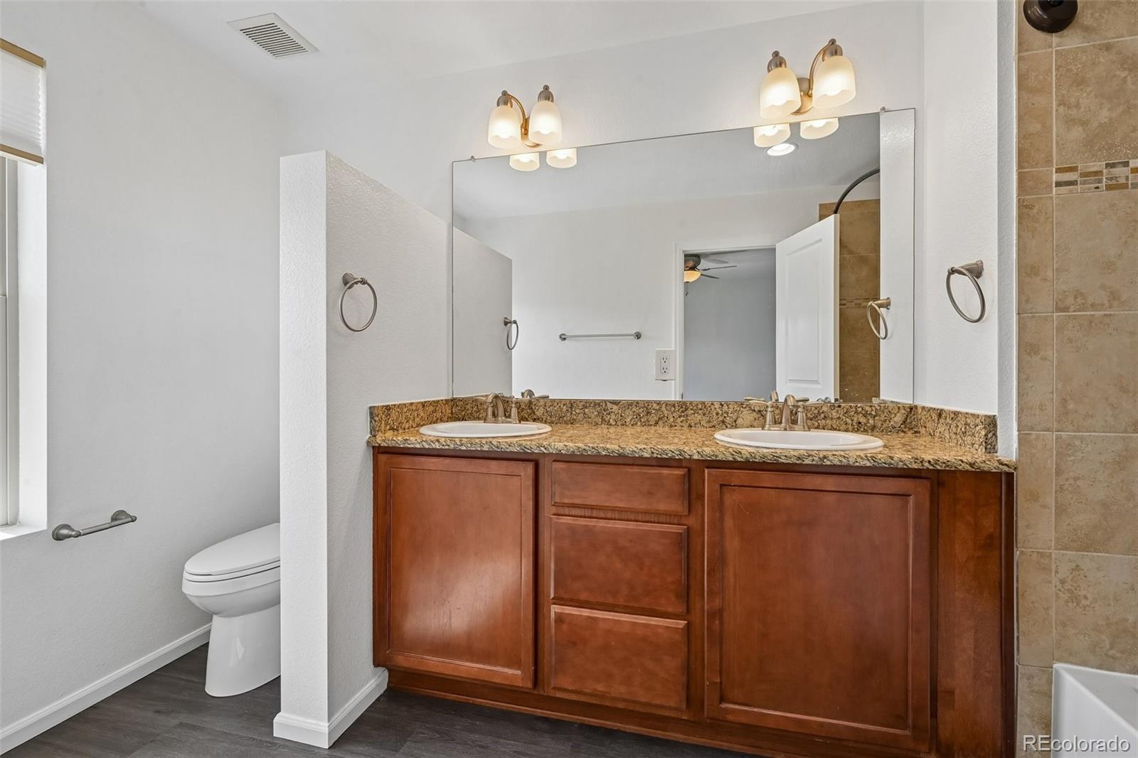 9520 Halstead Lane Lone Tree, CO 80124 - Photo 17 of 29 a bathroom with a granite countertop sink a toilet and a mirror