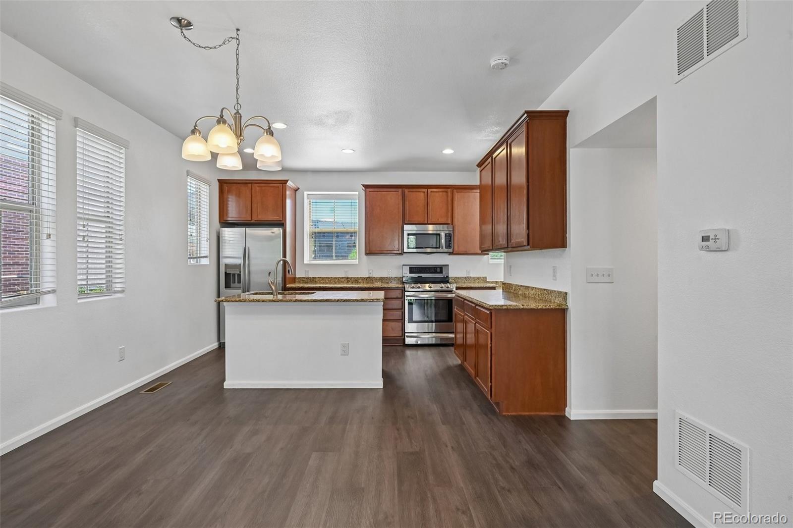 9520 Halstead Lane Lone Tree, CO 80124 - Photo 7 of 29 a kitchen with stainless steel appliances granite countertop wooden floors and white cabinets