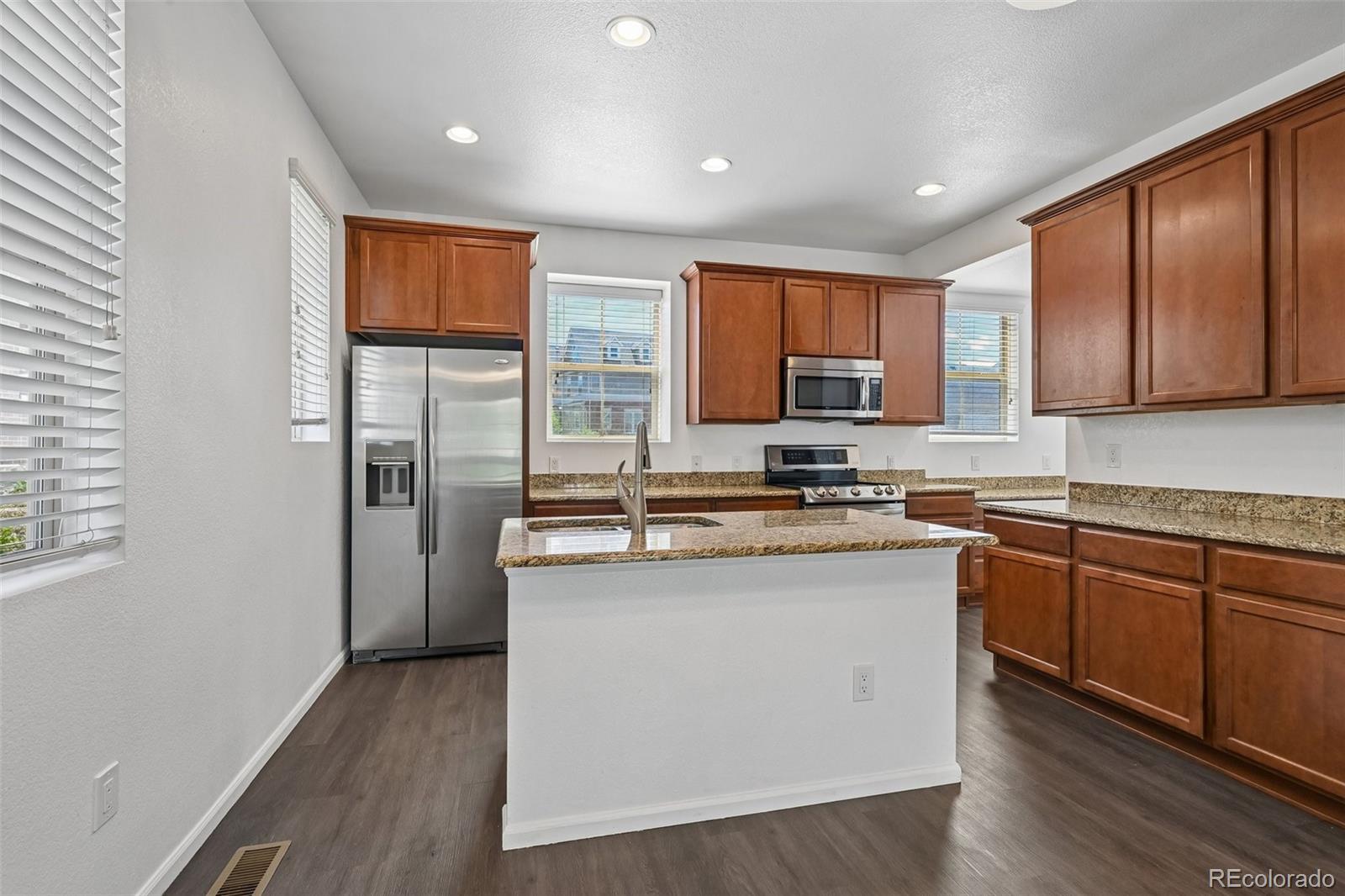 9520 Halstead Lane Lone Tree, CO 80124 - Photo 9 of 29 a kitchen with stainless steel appliances granite countertop a stove a sink dishwasher a refrigerator and a microwave oven with wooden floor