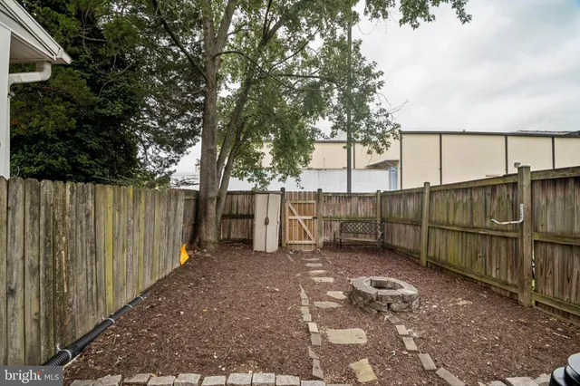 a view of backyard with wooden fence and large trees