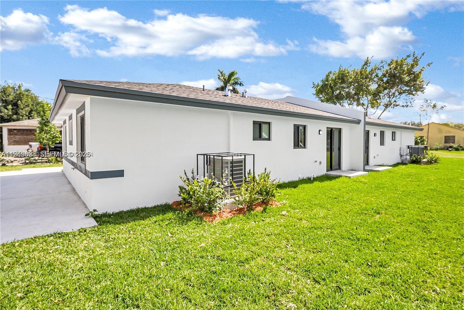673 Northwest 14th Street, Unit 1 Florida City, FL 33034 - Photo 18 of 21 a white house that has a small yard and a lot of flower plant in it