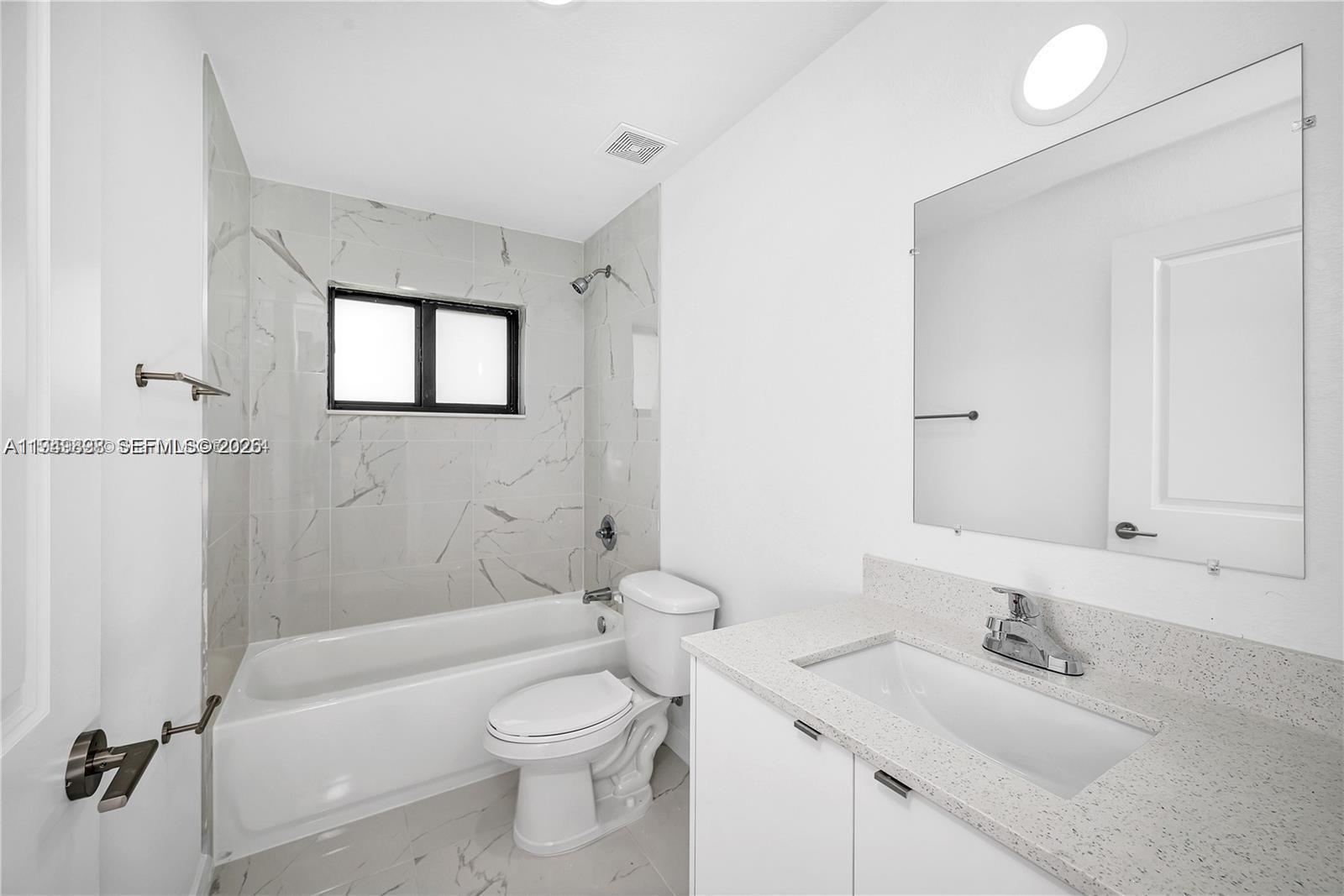 673 Northwest 14th Street, Unit 1 Florida City, FL 33034 - Photo 10 of 21 a bathroom with a toilet a sink a mirror a bathtub and vanity