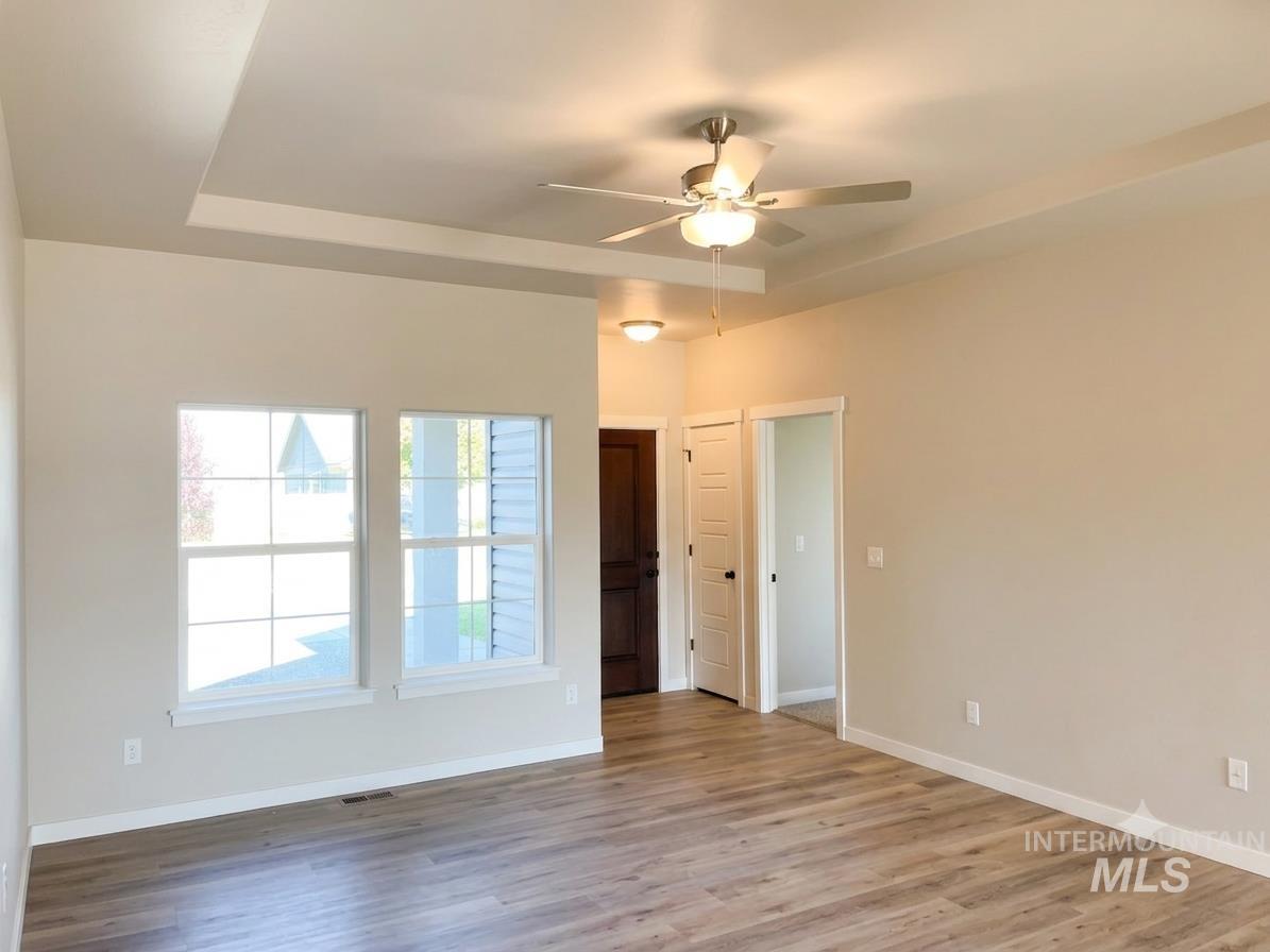 994 Kenbrook Loop Twin Falls, ID 83301 - Photo 3 of 10 Spacious room featuring a tray ceiling with a ceiling fan, two large windows, wood-finish flooring, and light-toned walls