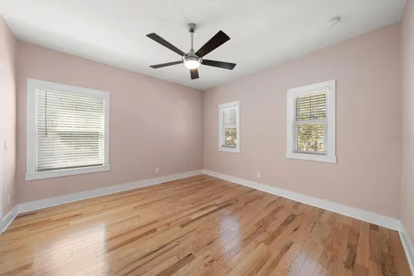 a view of empty room with wooden floor and fan